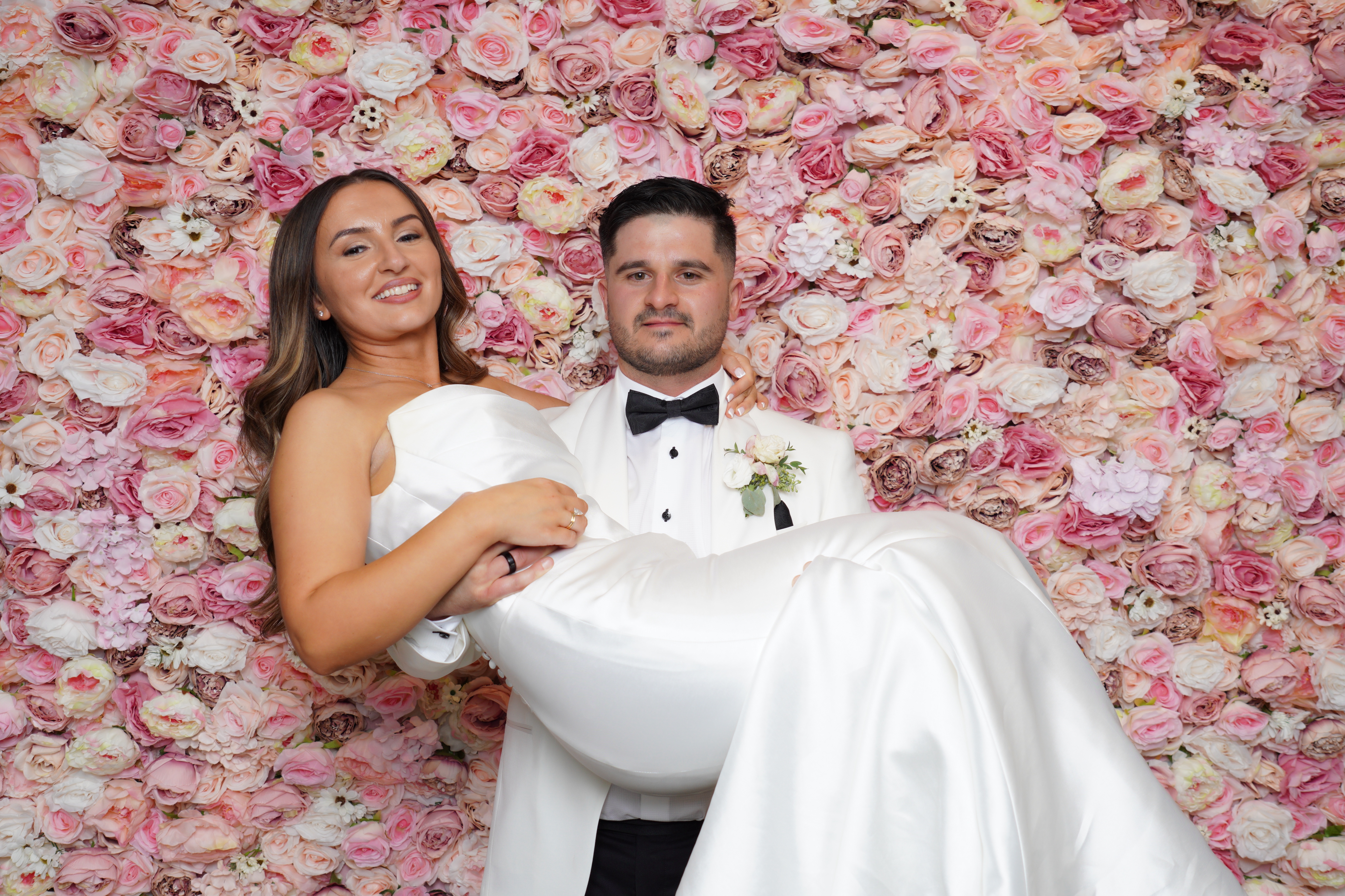 Bride and groom enjoying the DSLR Photo Booth in front of a pink floral backdrop